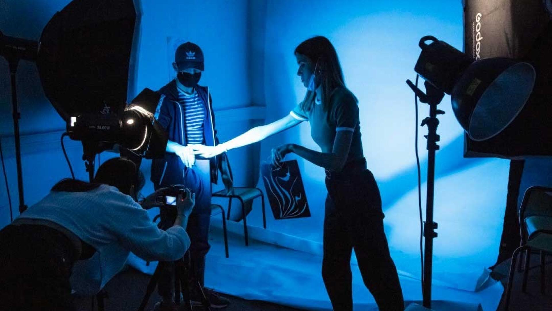 Des étudiants en train de réaliser une vidéo dans un studio aux éclairages bleus